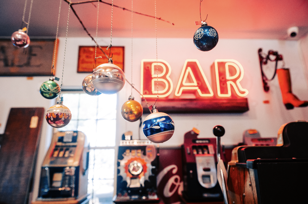 Festive Franklin Finds: Where to Find the Best Local Holiday Gifts Vintage bar with neon sign, hanging ornaments, slot machines, and antique decor in Williamson County, Tennessee.