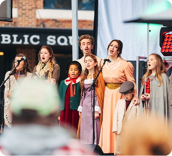 Dickens of a Christmas A diverse group of children and adults dressed in period costumes perform a musical number on an outdoor stage in Williamson County, Tennessee.