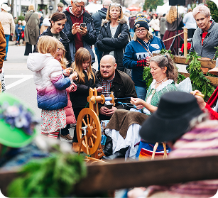 Dickens of a Christmas A group of people, including children, gather around a man spinning yarn on a wooden wheel at a public event in Williamson County, Tennessee.