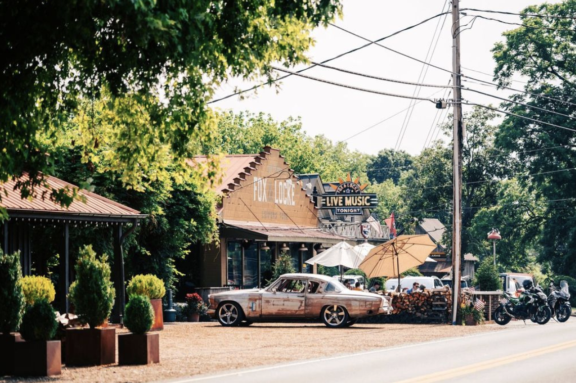 Leiper's Fork, Tennessee: The Revival of a Small-Town Gem A vintage car sits outside a live music venue with outdoor seating and umbrellas in Williamson County, Tennessee.