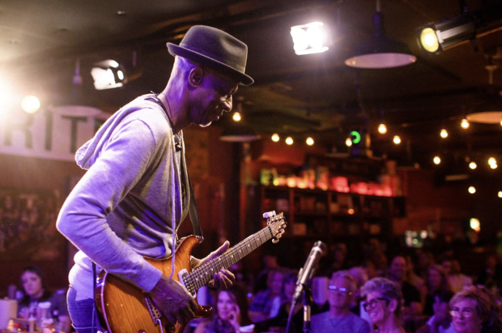 Leiper's Fork, Tennessee: The Revival of a Small-Town Gem A musician wearing a hat plays an electric guitar on stage in a dimly lit venue in Williamson County, Tennessee.