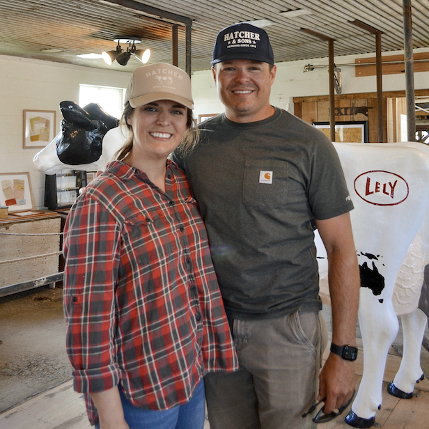 How Williamson County’s Farms Draw in Visitors and Keep History Alive A smiling couple stands in a barn with a cow statue, wearing casual farm attire in Williamson County, Tennessee.