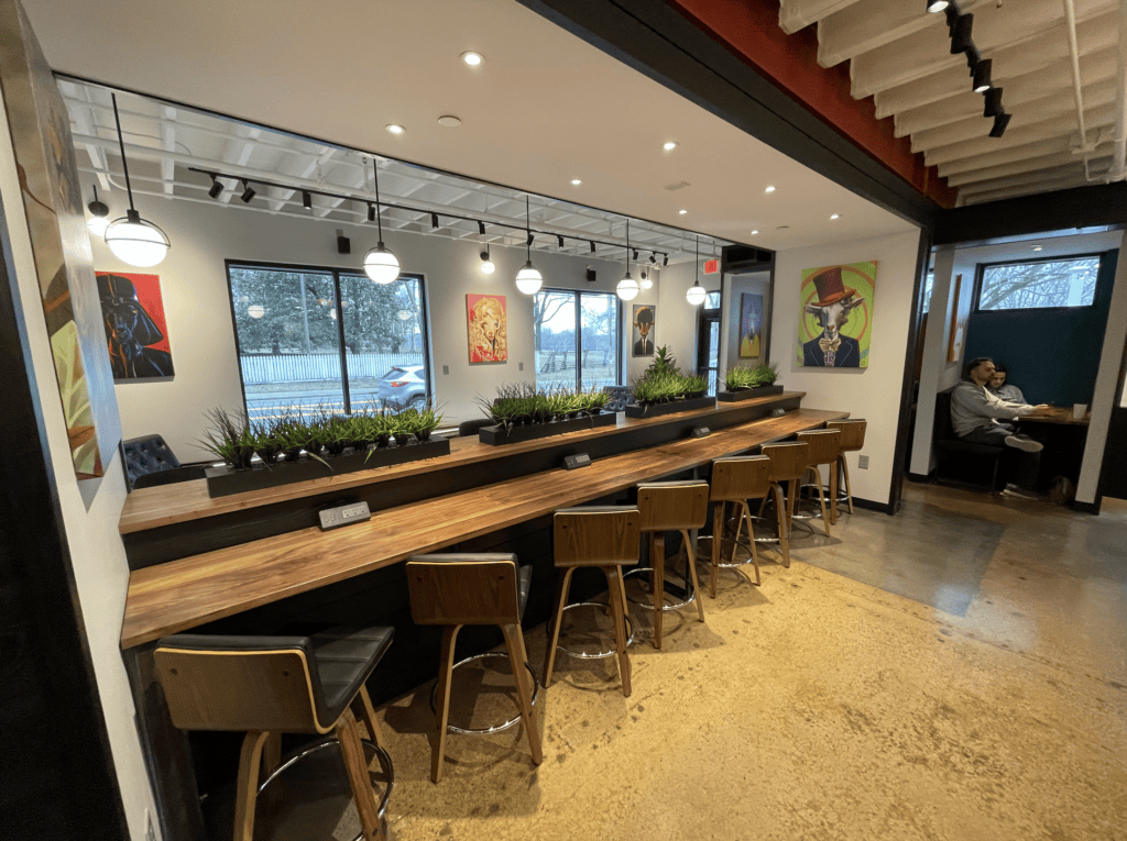 Modern cafe with long wooden bar, stools, plants, and colorful wall art in Williamson County, Tennessee.